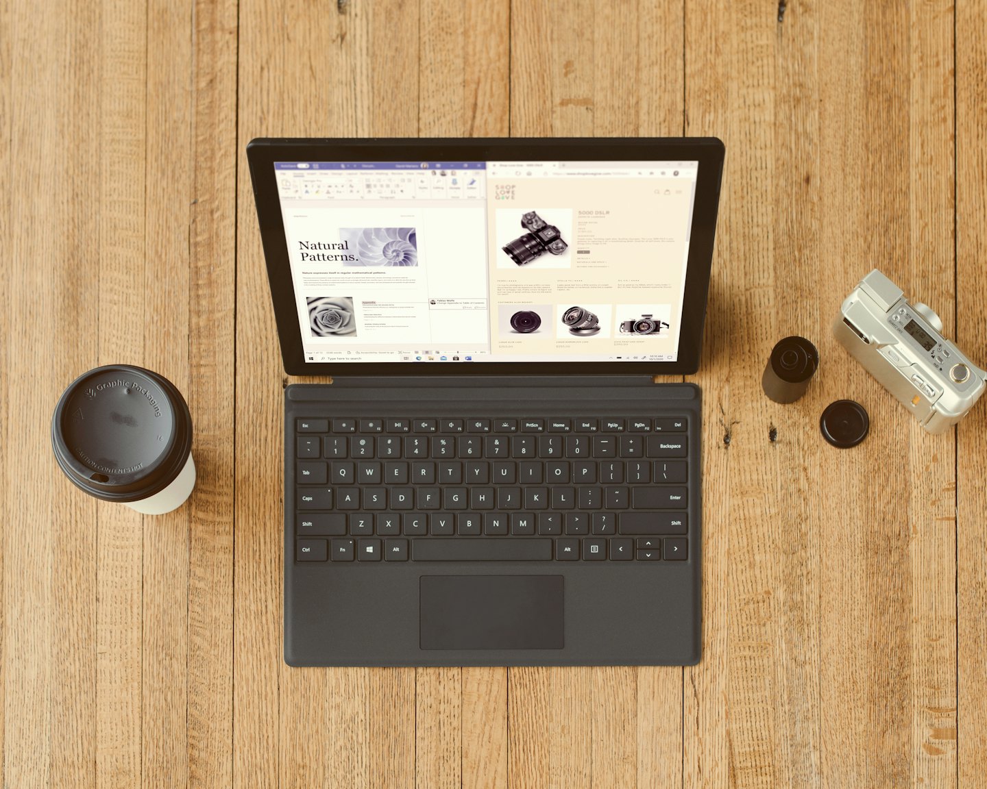 Laptop, kubek kawy i aparat na drewnianym biurku.